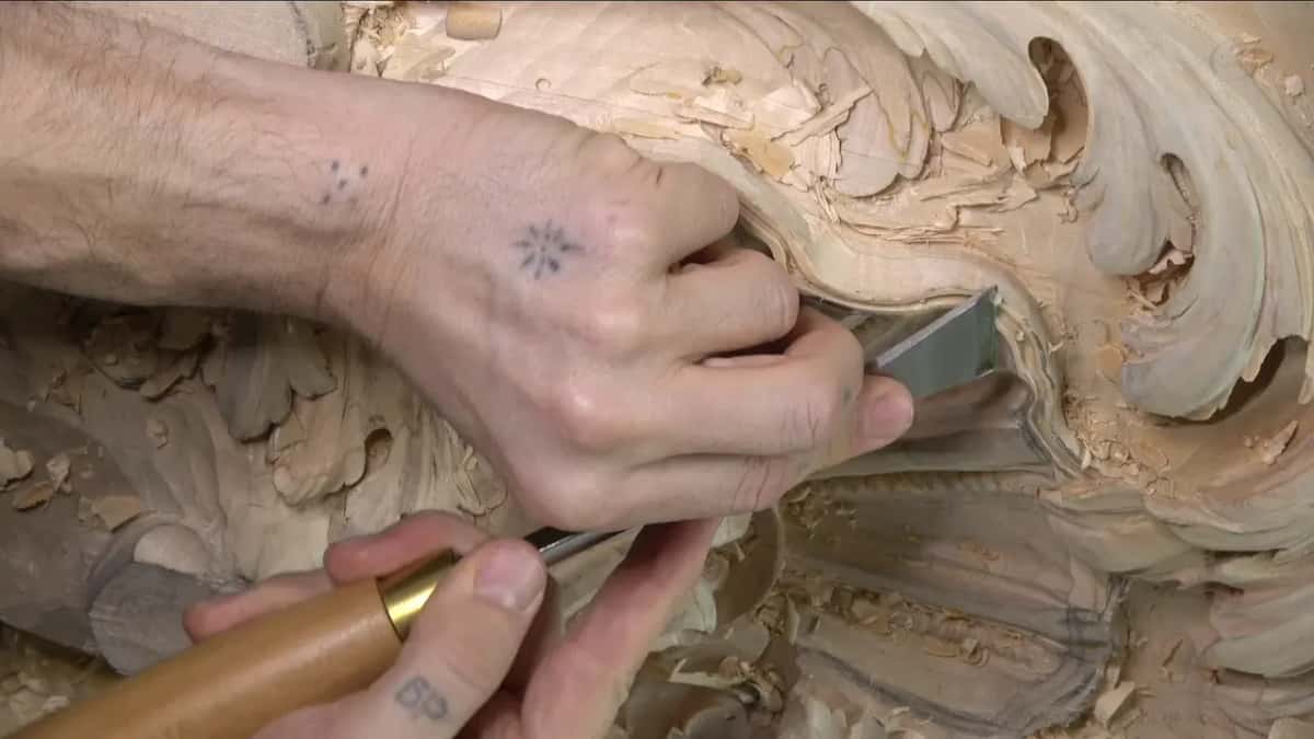 Flat blade with a brass ferrule shaves along the edge while the other hand presses down from above.