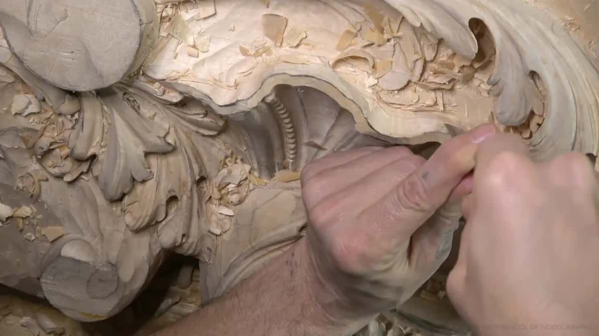 Two hands work a gouge along the upper rim.