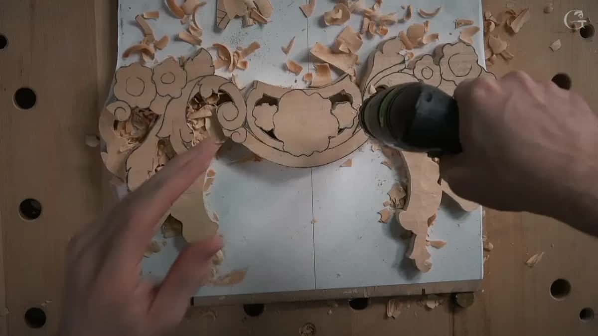 Both hands steering the drill through the panel