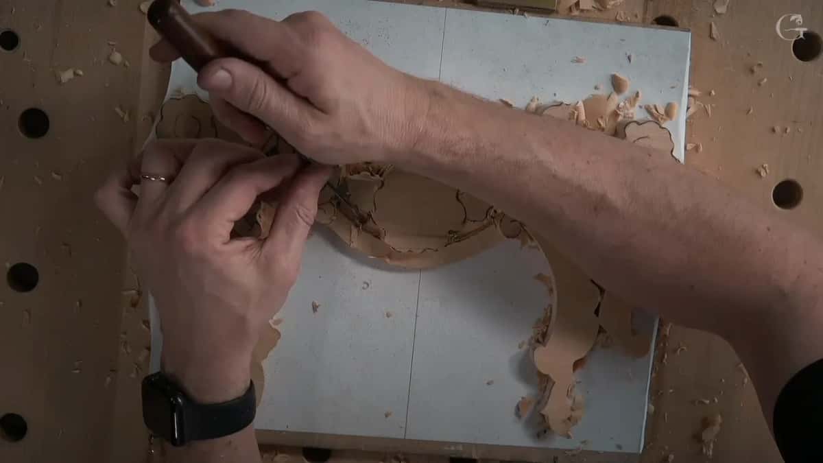 Flat tool held upright on the drawn line with a mallet ready to tap it, gently, because the ground is thin