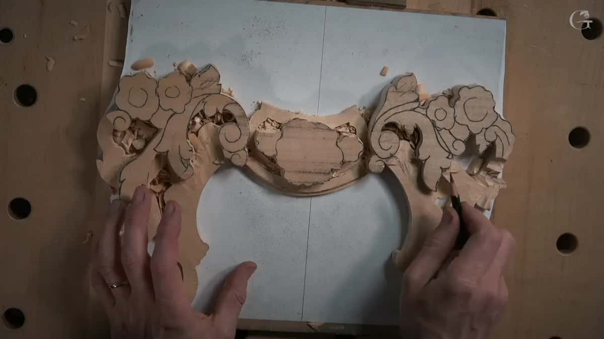 Both hands resting on the ornament with the ground already opened and the design still drawn across the shapes in pencil