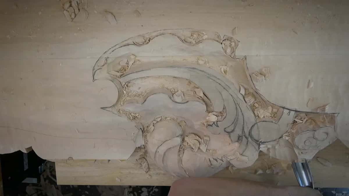 Pencil lines for the acanthus run around the roughed shell while a gouge works low on the right
