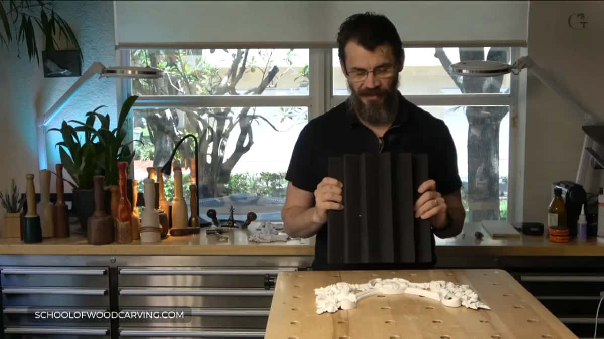 Black ribbed acoustic foam panel held up in both hands