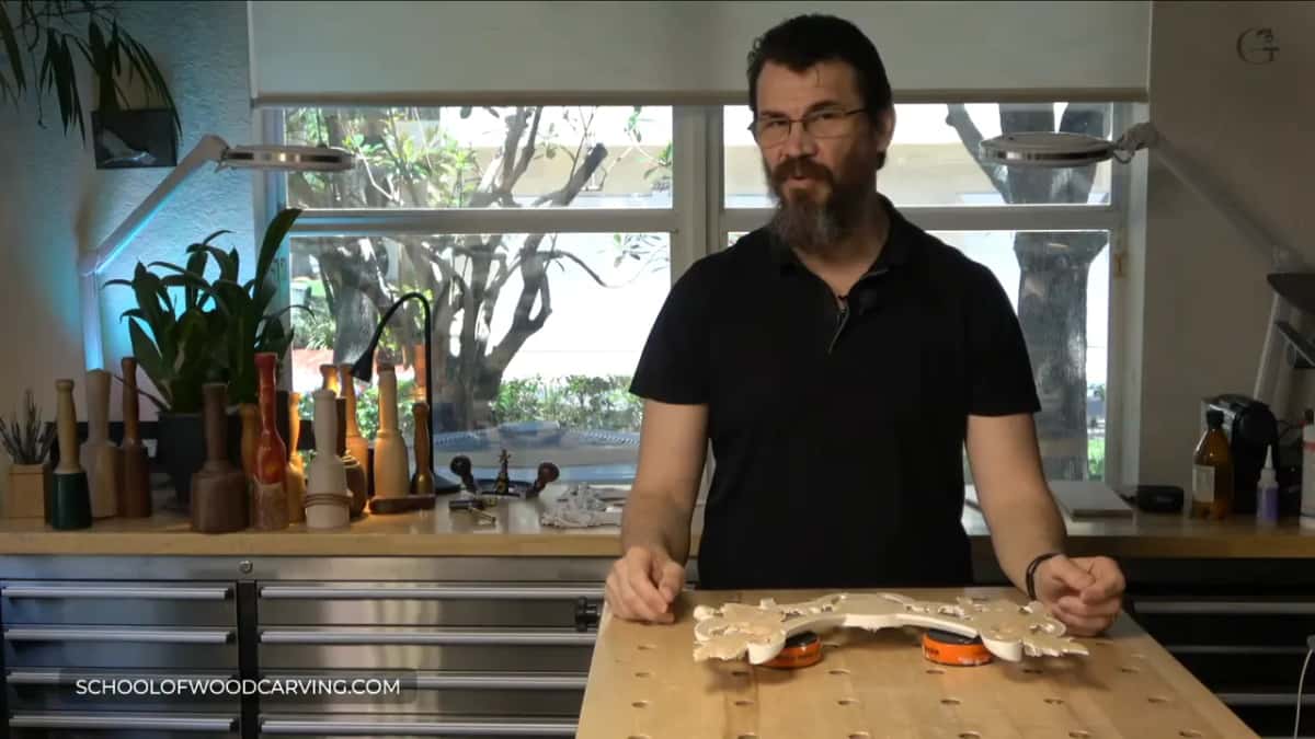 Carving propped on two orange bench cookies, both hands resting beside it