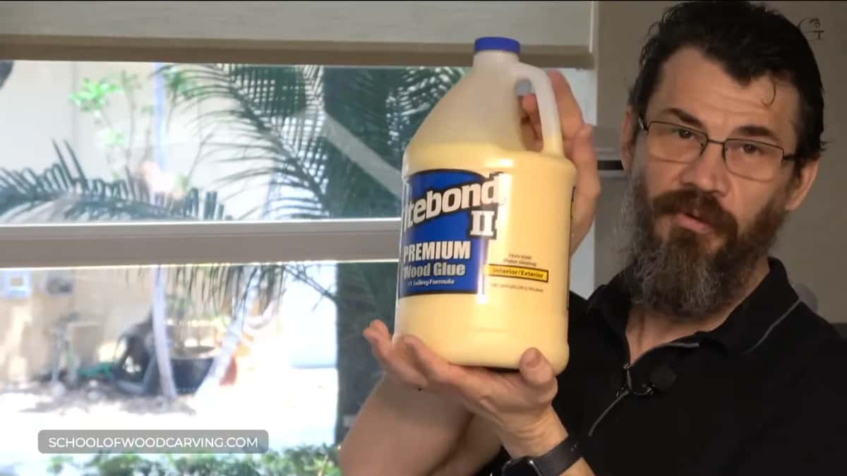Gallon jug of Titebond II Premium Wood Glue held up beside his face