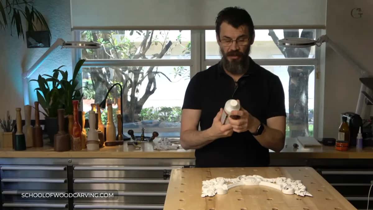 White bottle of wood hardener in his hands