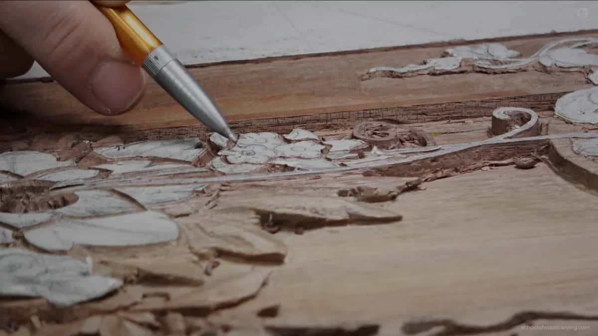 A pencil marking the wood where the next small flower will go, with pattern paper still stuck down around it.