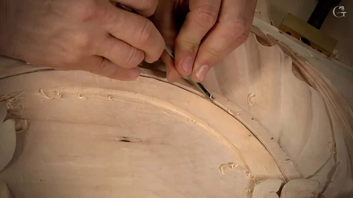 Two hands on the tool, the groove dark beneath it