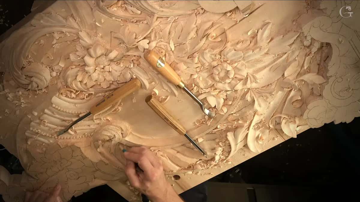 Three gouges lie on the carved flowers while a pencil draws near the shell