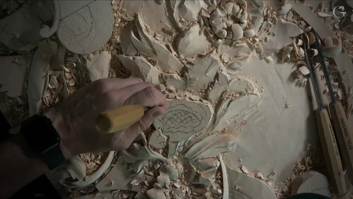 A fist around a gouge handle at the flower's edge
