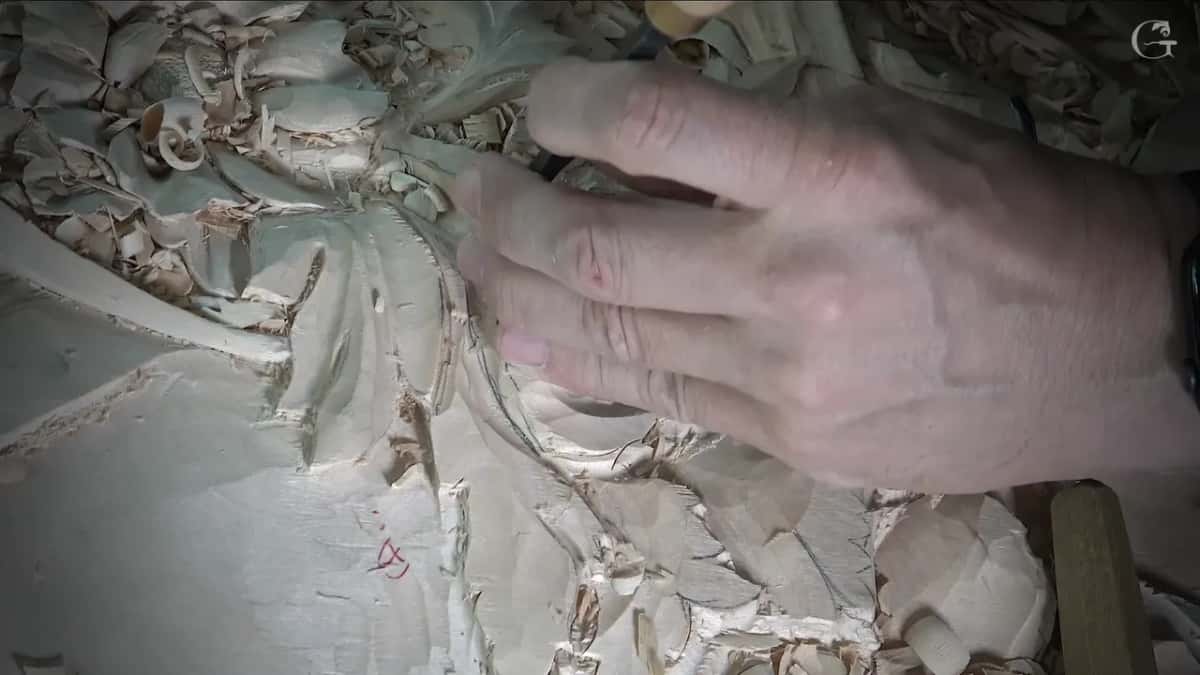 Fingertips press a tool straight down near the leaves