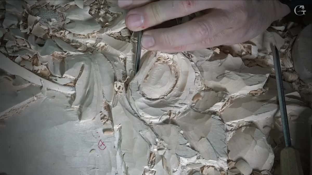 Thin tool held upright at the petal edge, a red mark on the ground
