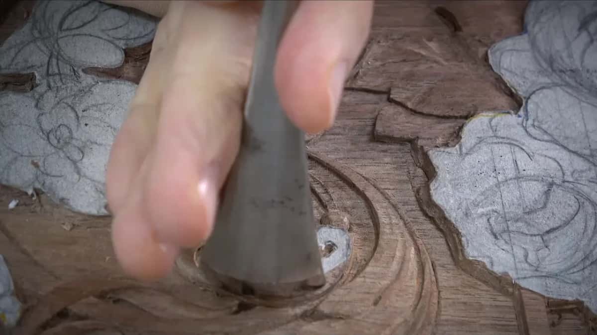 Broad grey blade buried in the spiral, fingers wrapped over the handle above it