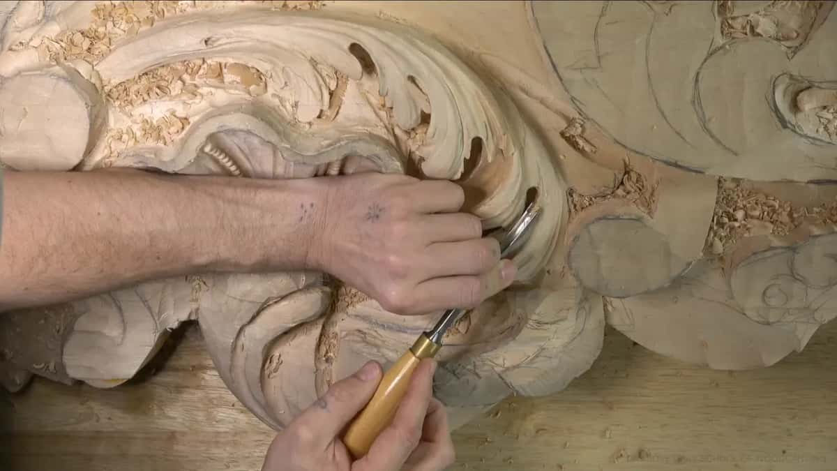 Curved shank on a yellow handle rides along a pipe, fingers of the left hand bracing the blade.