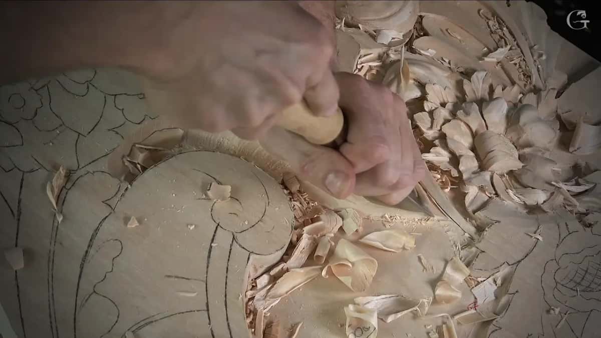 Both hands close together on one short tool, chips piled in the hollow around them
