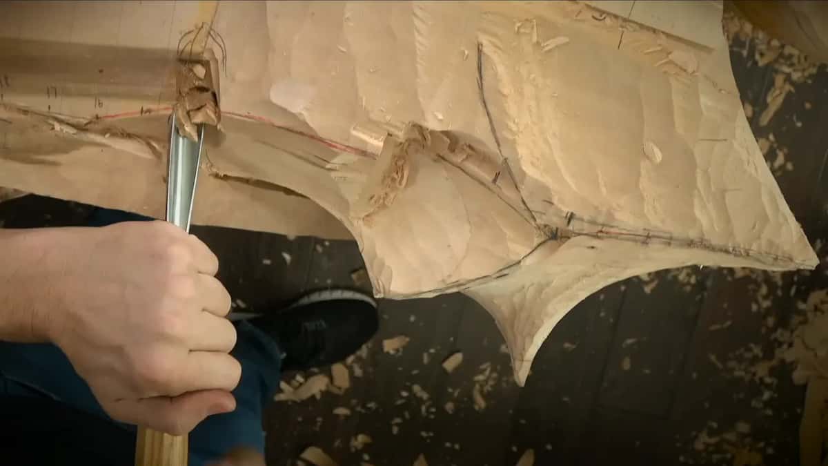 One fist pushes a gouge straight down into the carving beside a raised lump