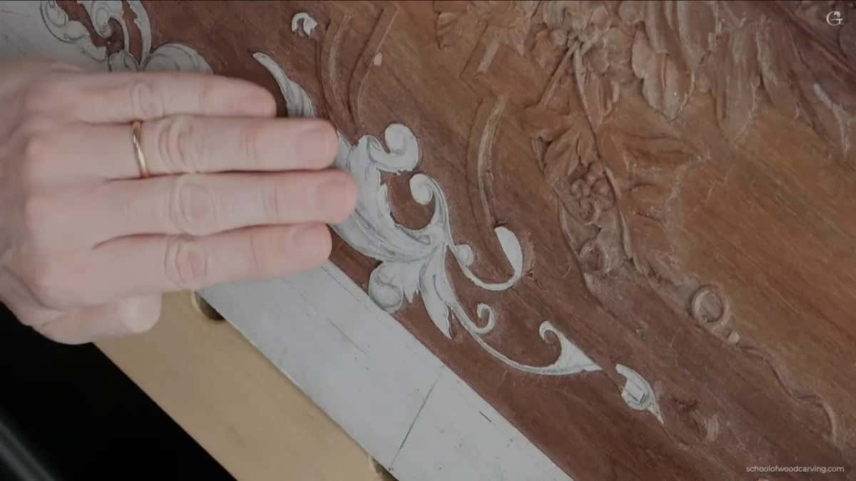 An open hand laid across the carved scrolls he works on today.
