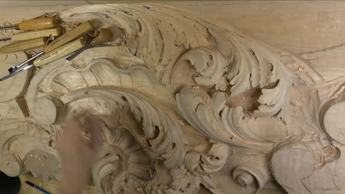 Seen from above, the whole carved board, with a row of gouges lying across its top left corner.
