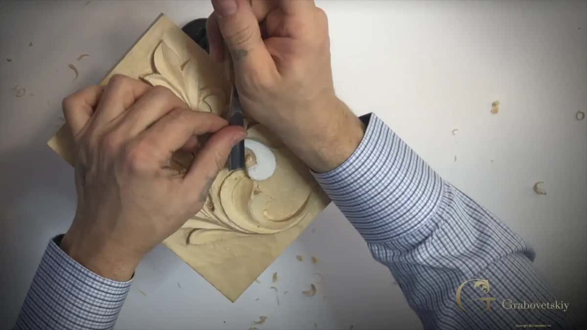 Forearms on both sides of the panel while a gouge runs beside the lower curl