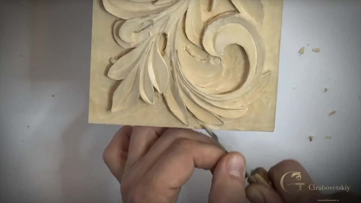 Fingers under the panel, one tool angled in toward a leaf