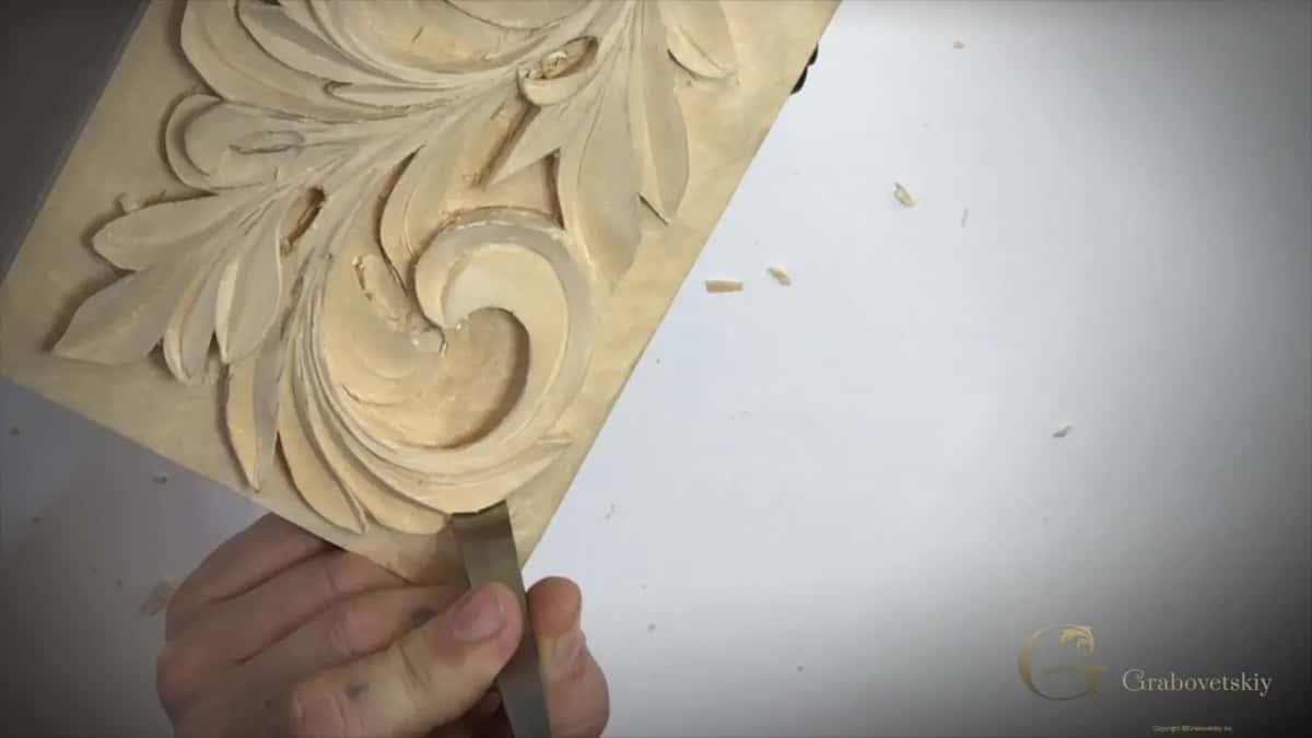 Fingers pinch a flat blade below the big curl