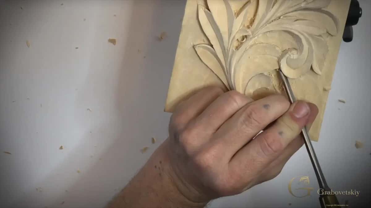 Straight gouge working inside a curl near the bottom of the board, held in one hand
