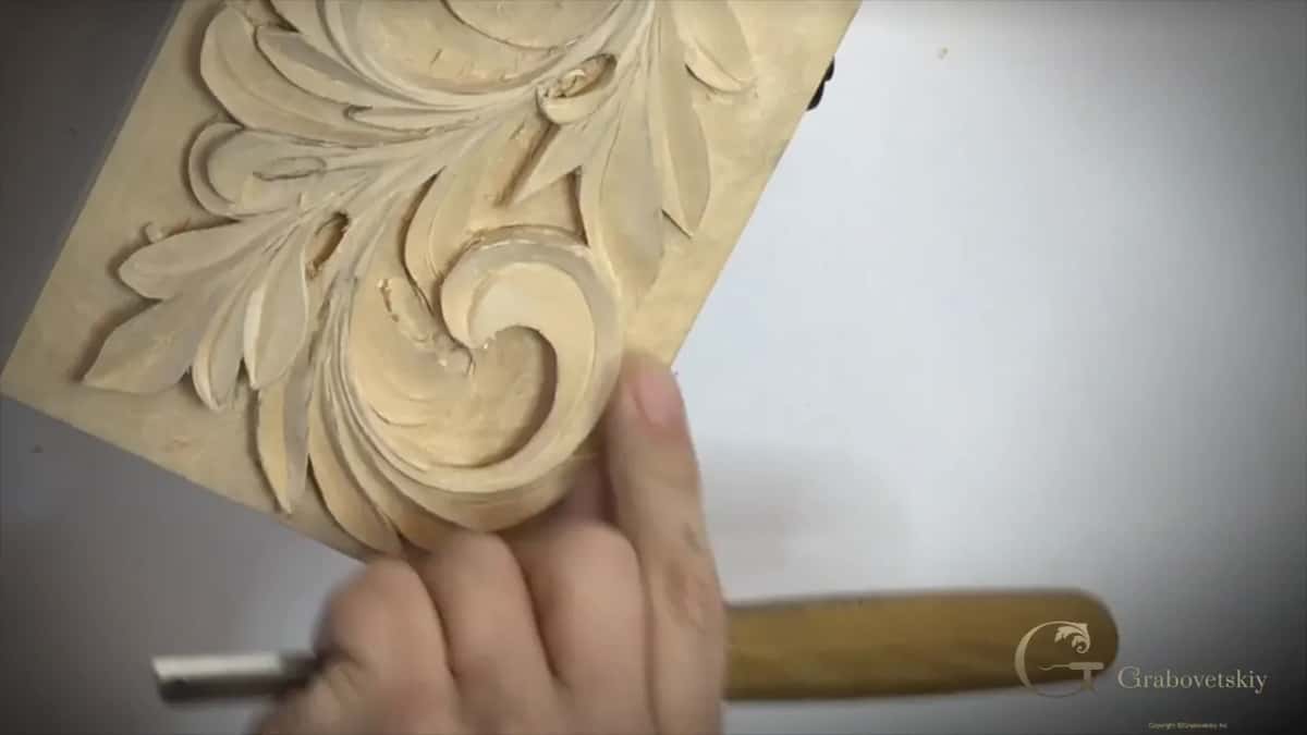 Light handled tool held sideways along the panel's lower side, thumb pressed on the wood