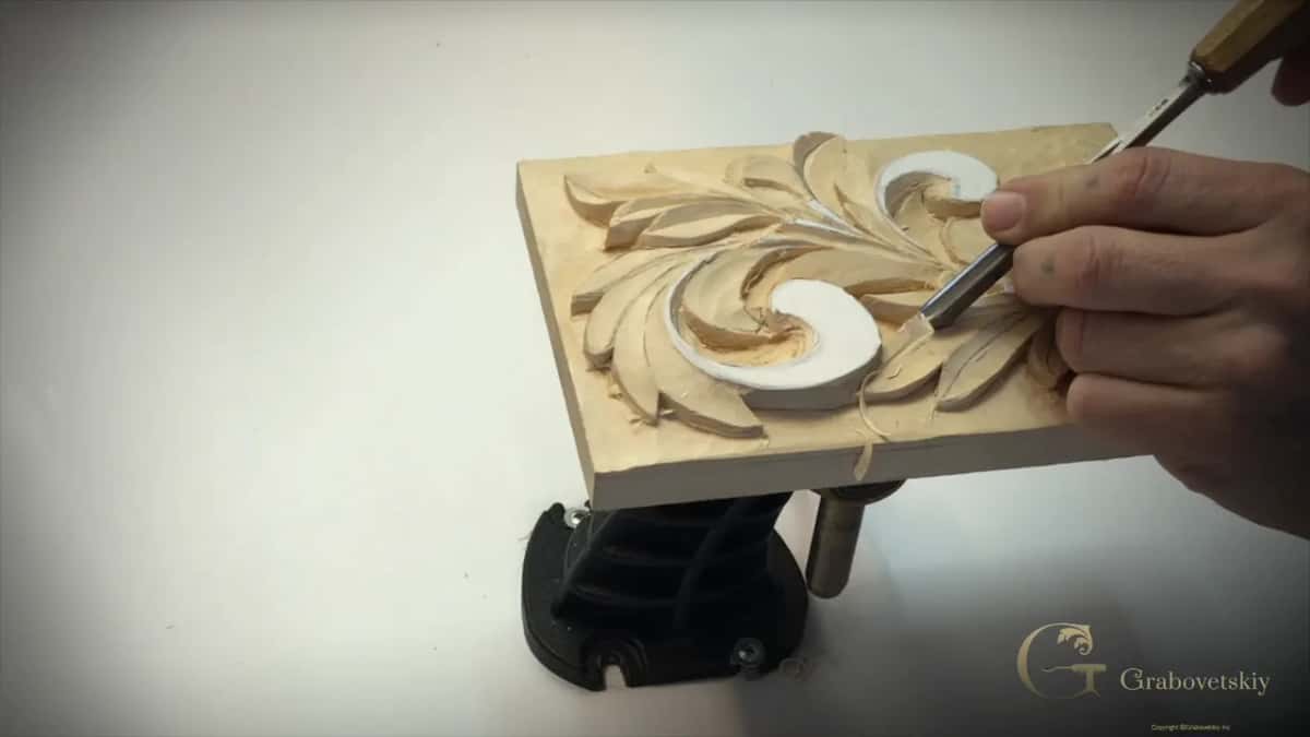 Panel lying flat on its stand while a V tool goes into a lobe beside the lower curl