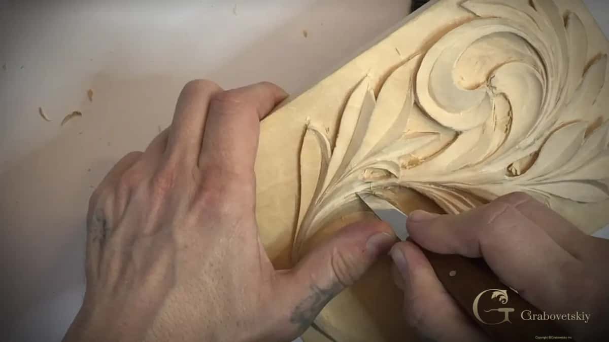 Two hands on a knife at the lower left of the panel, the upper curls above it