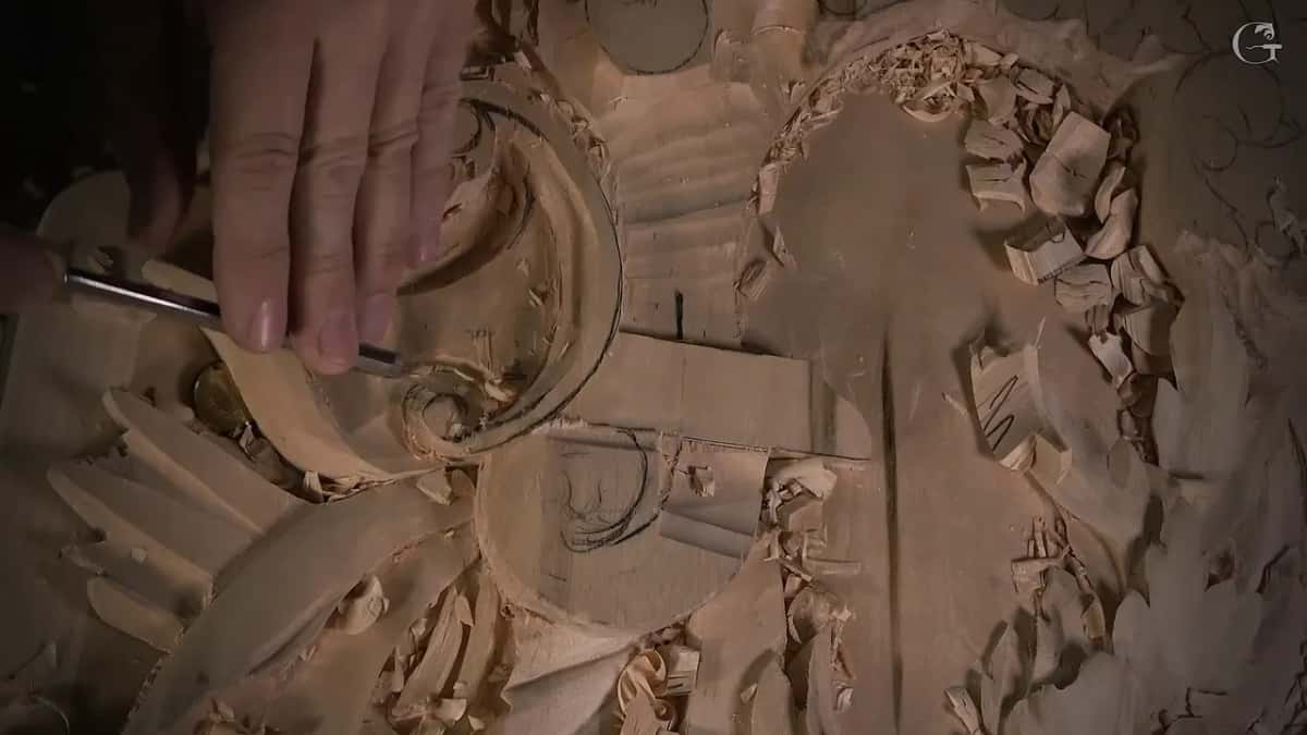 Spare wood still left on a volute while a slim tool works beside it