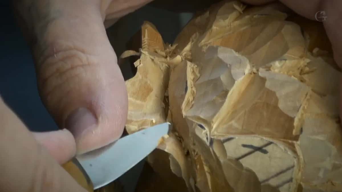 Knife laid almost flat against the carved petals.