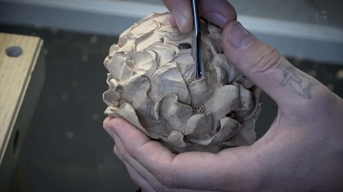 Both hands on the flower, tool at the upper right.