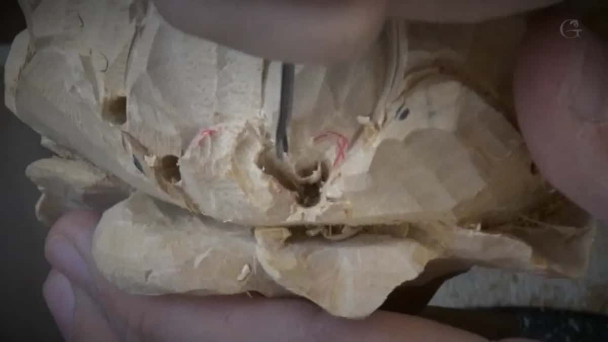 Held in the fingers, with the petals carved deep enough that the join between them has gone black.