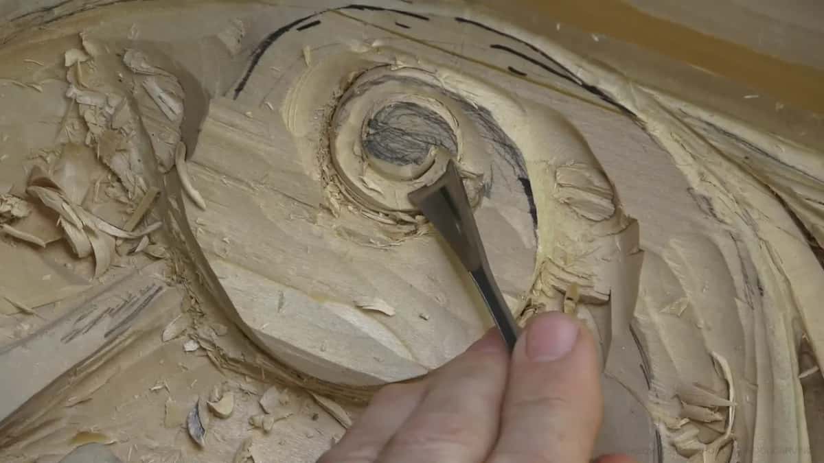 Steel edge going straight down beside the hatched core while shavings pile up on the left.