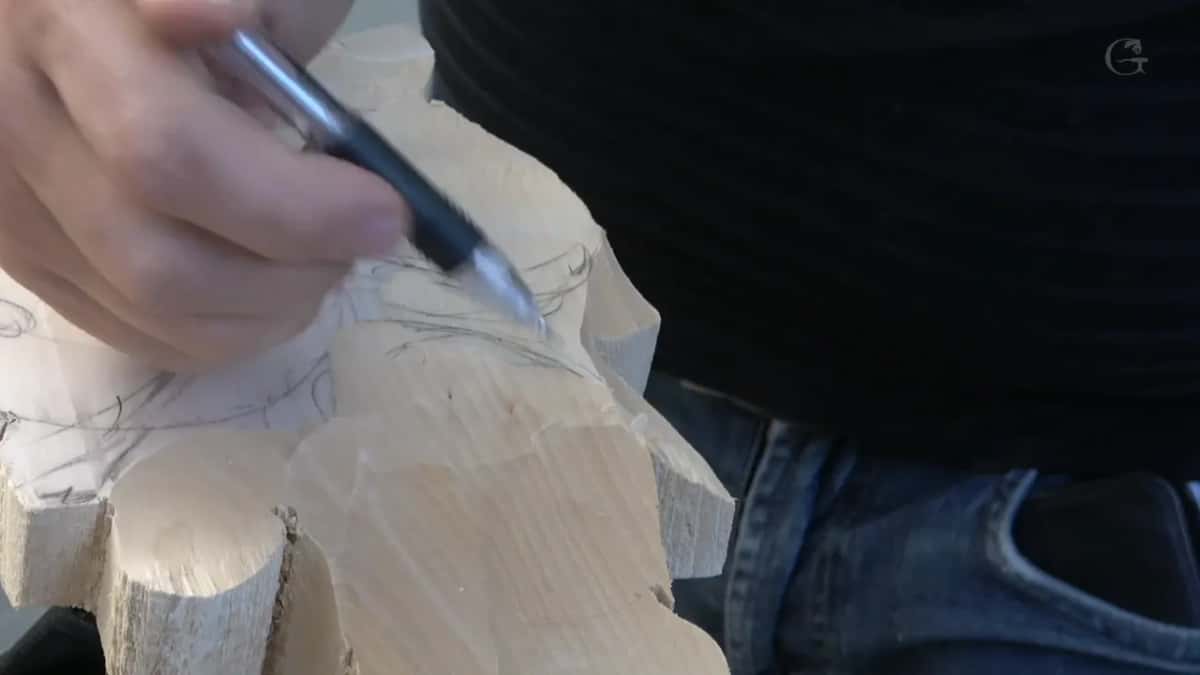 Mechanical pencil redrawing a flower outline on wood that has already lost its first layer of waste