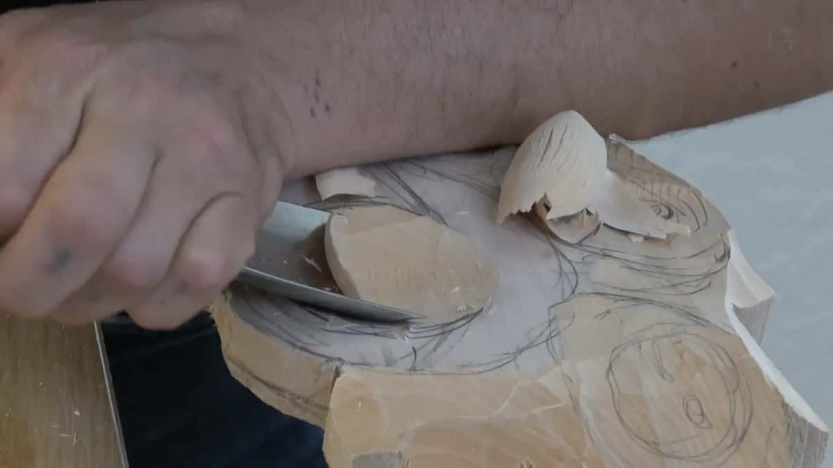 Narrow gouge lifting a chip clear of the pencilled flower outline