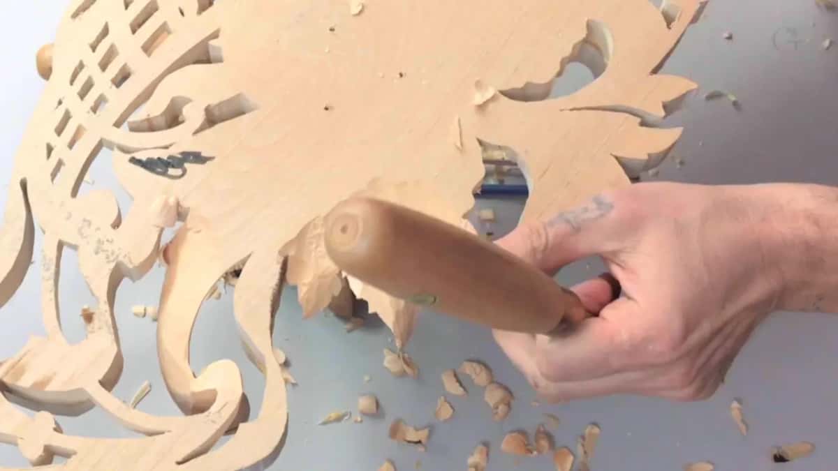 Gouge handle in one hand, its blade under a leaf on the reverse