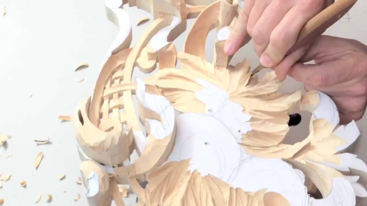 Hands at work on the front face, chips collecting around the pattern.