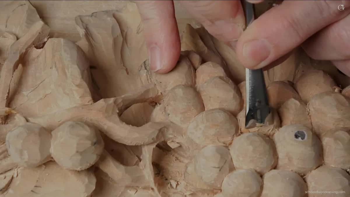 Wide chisel taking one light shaving off a single berry, with facets left by earlier passes still showing clearly