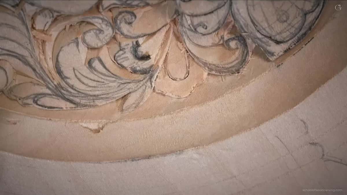 Carved leaves and one small flower at the bottom edge, pencil lines still showing on the wood