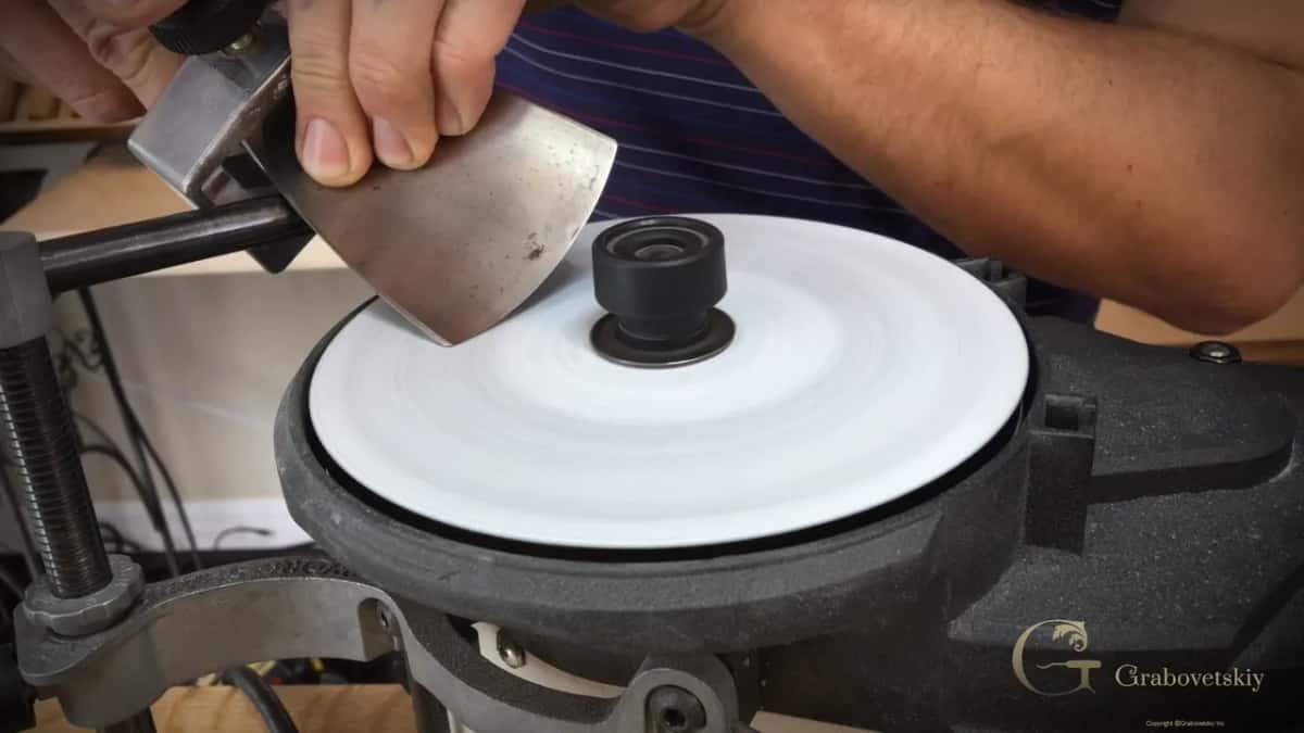 Wide bevel pressed against the spinning disc, the wheel blurred white beneath it.