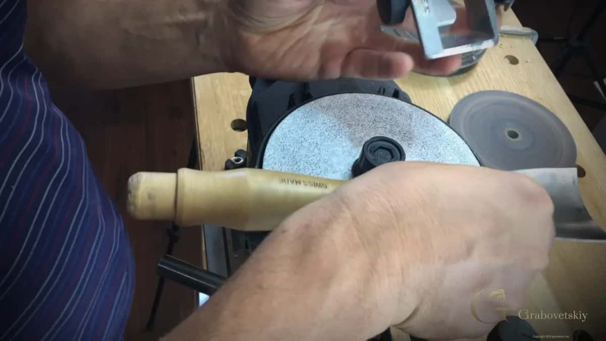 Pale handle stamped SWISS MADE lies across the machine next to the coarse grey disc.
