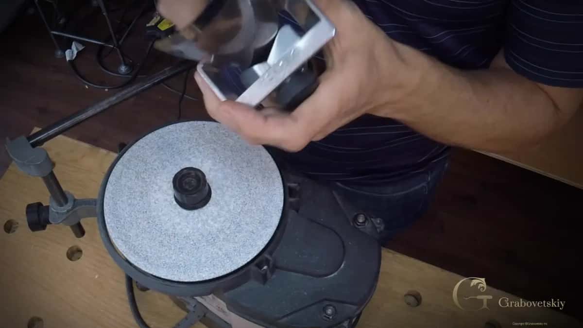 Whole grinder seen from above: grey disc on the platen, the Tormek support bar bolted to the bench at the left.