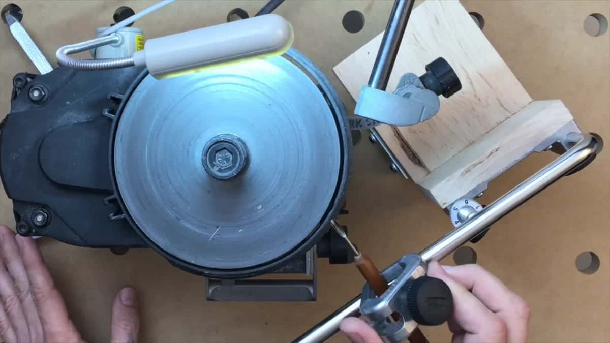 A Tormek jig holding a small gouge, riding the bar above the machine, seen from directly overhead.