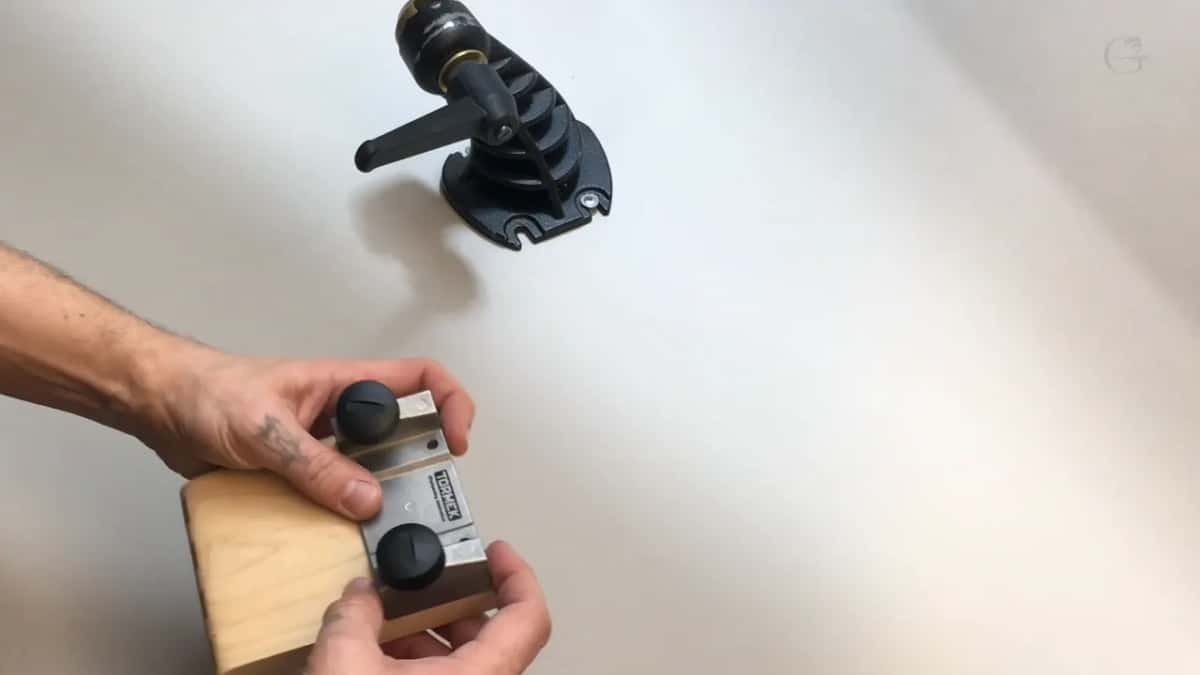 New bracket in his hands and the old cast mount above it, so the two can be compared.
