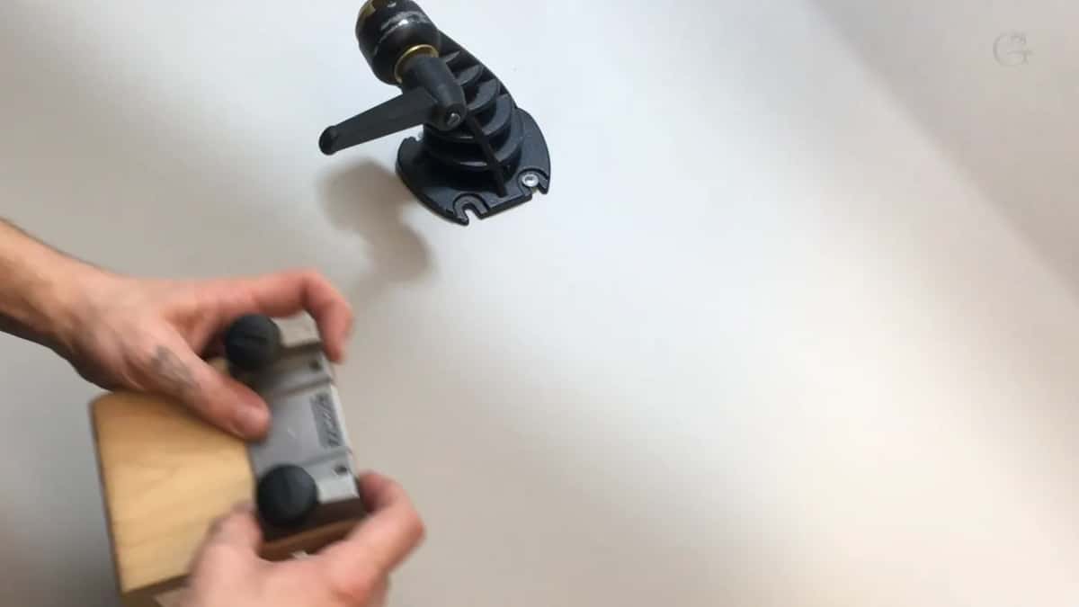 The discontinued Work Sharp mount, cast black, lying on the bench.