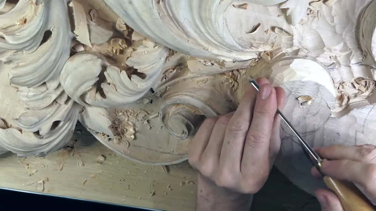 Fingertips guide the slim gouge along a leaf edge.
