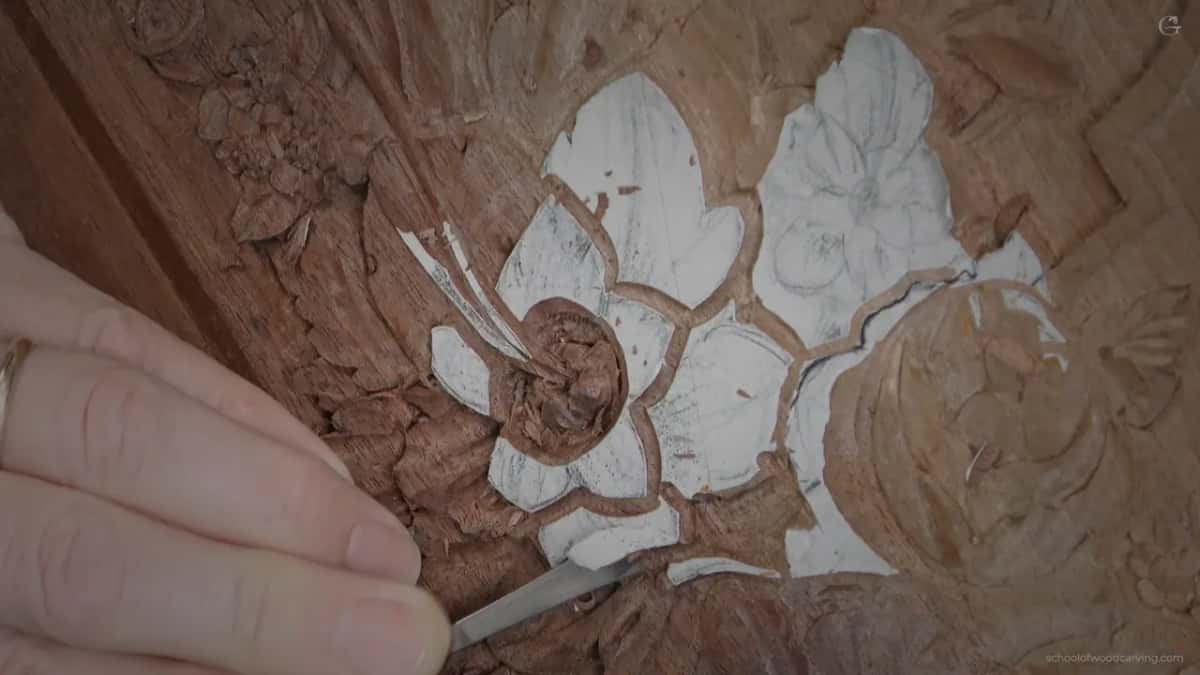 A hand with a flat tool dropping a small bead beneath the detail beside it, until a sixteenth of an inch is all that is left.