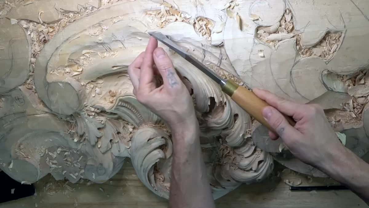 Pale handle and brass ferrule on a long chisel held across the upper shell, pencil lines around it.