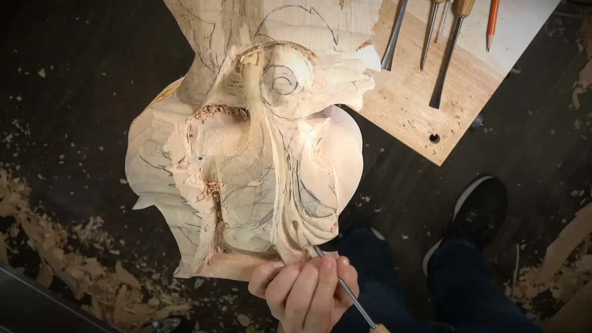 Right hand pushing a long gouge near the bottom of the block